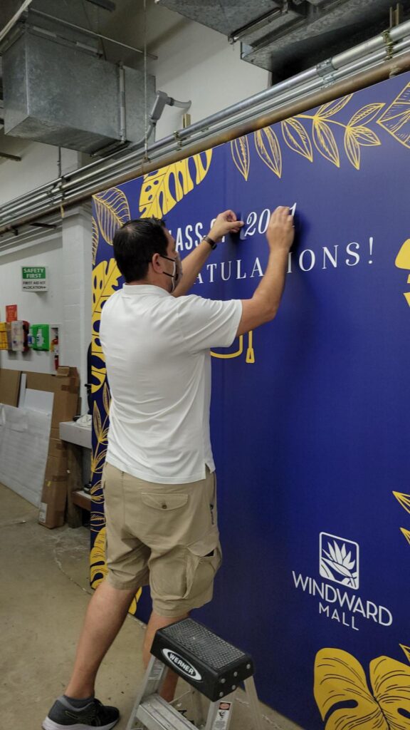 Closeup on man installing letters on blue wall