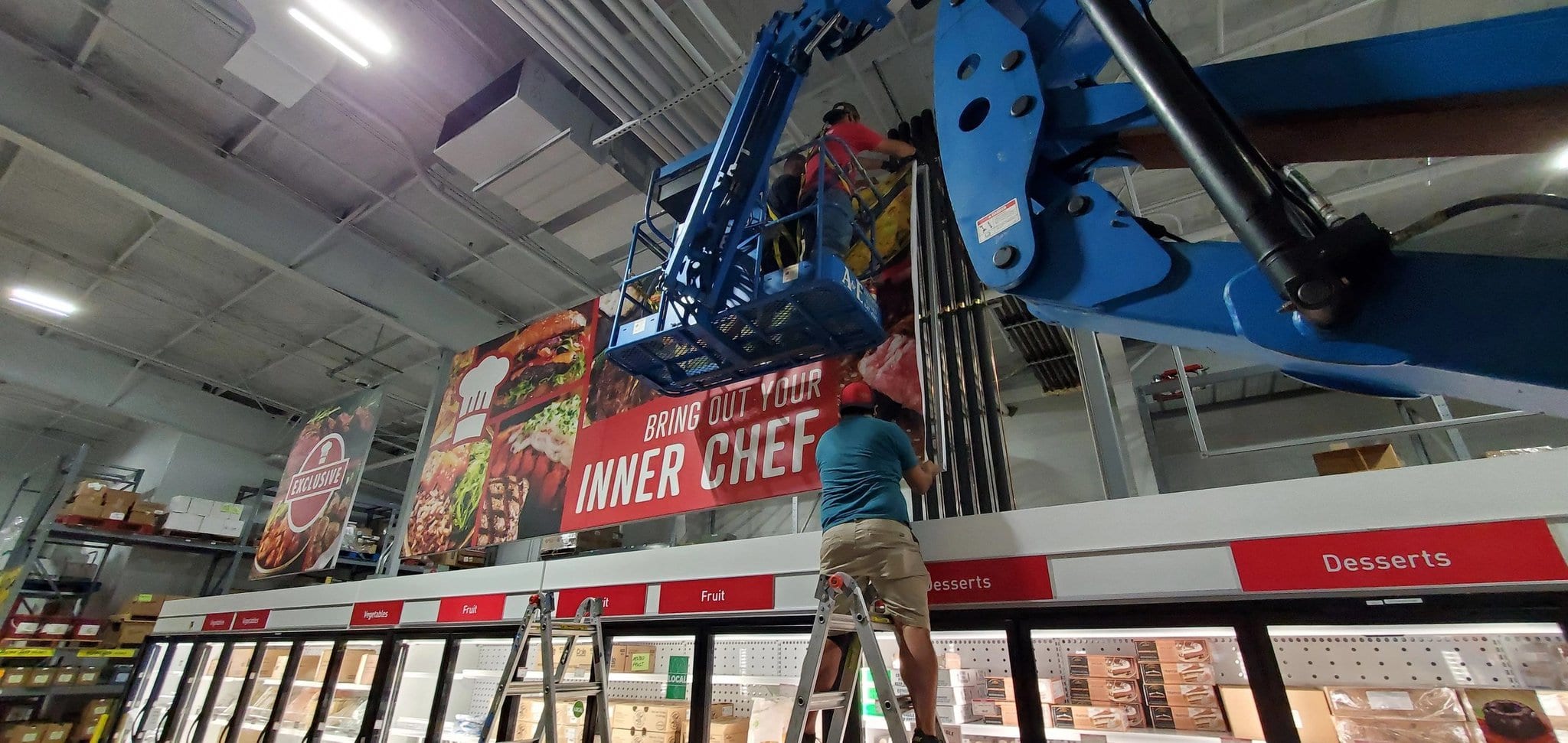 installer in crane putting up SEG fabric onto frame